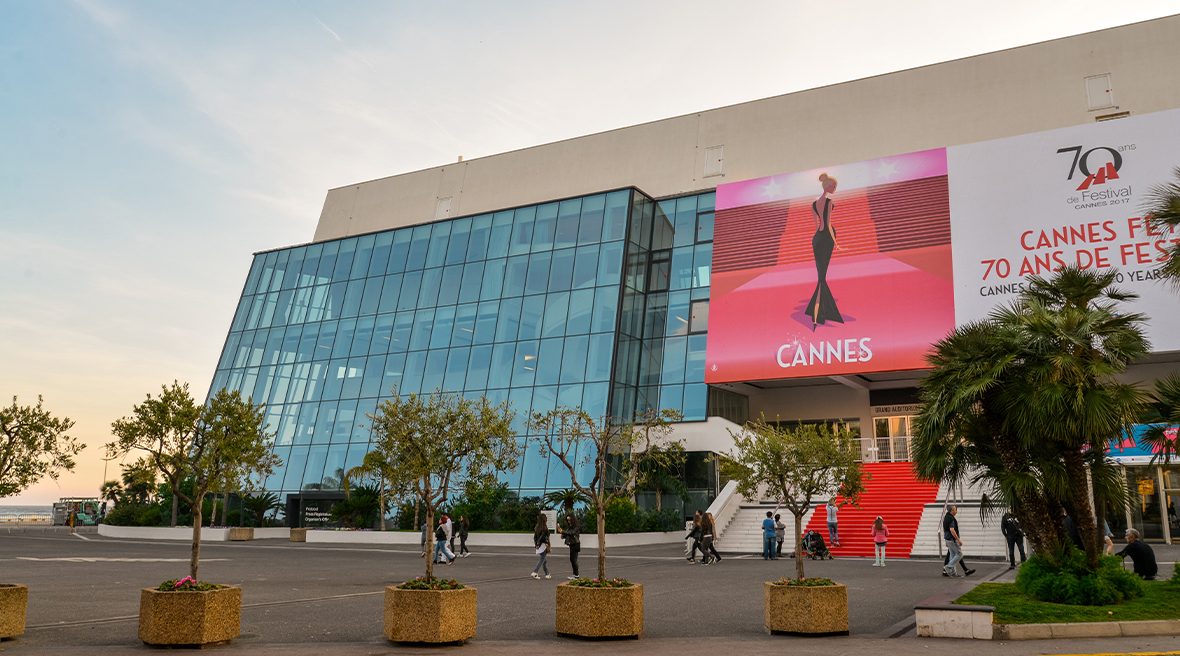 A large auditorium with a poster for Cannes Film Festival on it and trees marking the entrance